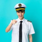 airplane-pilot-caucasian-woman-isolated-blue-background-surprised-pointing-front_1368-226180