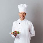 happy-young-cook-uniform-holding-salad