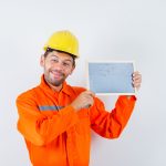 young-worker-holding-blackboard-uniform-helmet-looking-cheerful