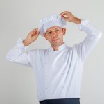 male-chef-uniform-apron-hat-posing-while-holding-his-hat