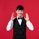 front-view-happy-satisfied-male-waiter-uniform-with-butterfly-neck-red-background-1